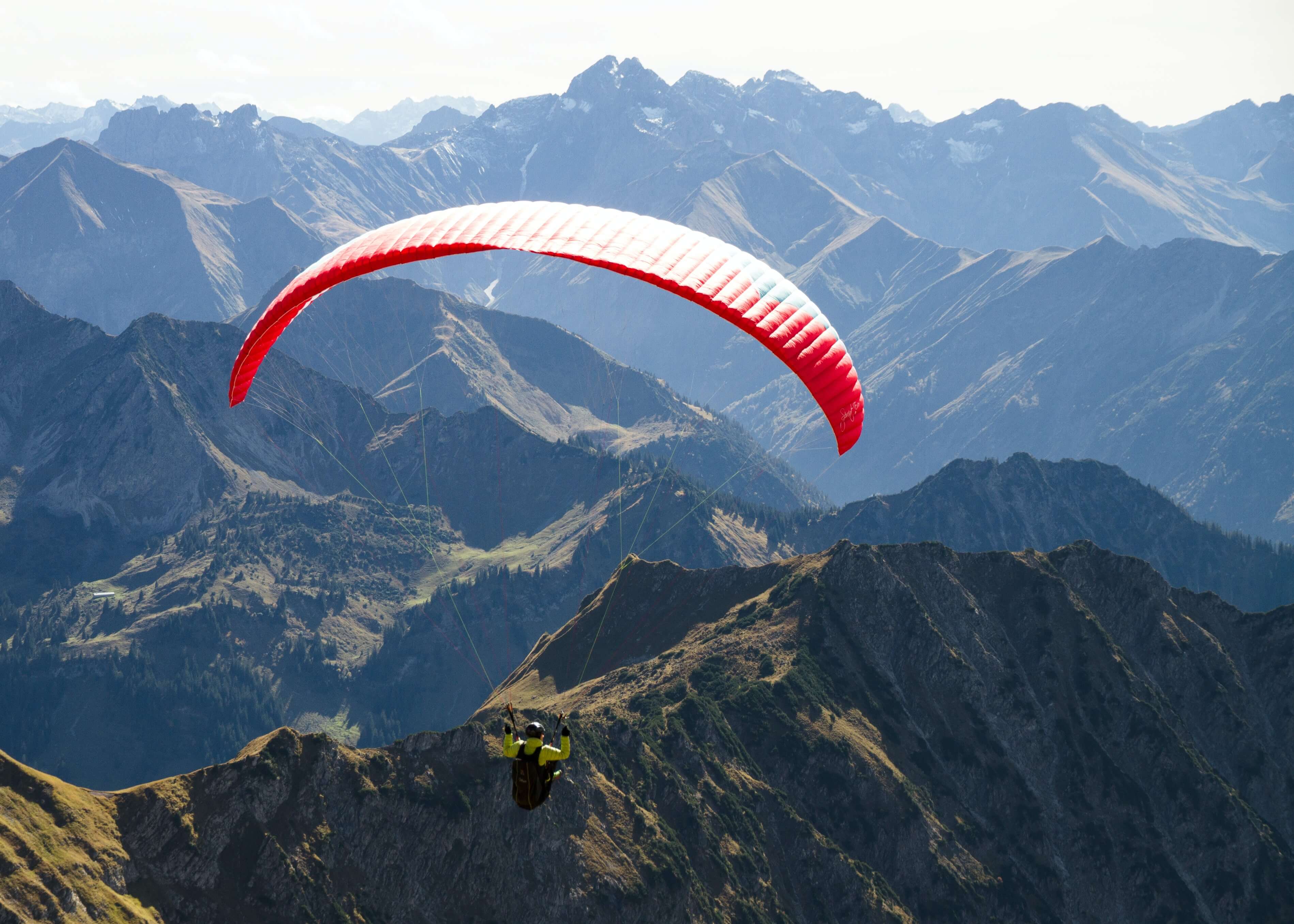 An image of somebody with a parachute gliding over the mountains